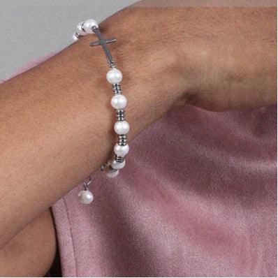 Adjustable Pearl and Titanium Steel Cross Bracelet — wrist-worn view over a muted pink shirt