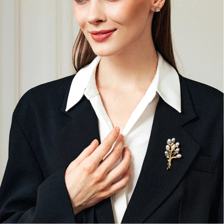 Two-Tone Pearl Bouquet Brooch — waist-up model view with the brooch pinned on a dark blazer