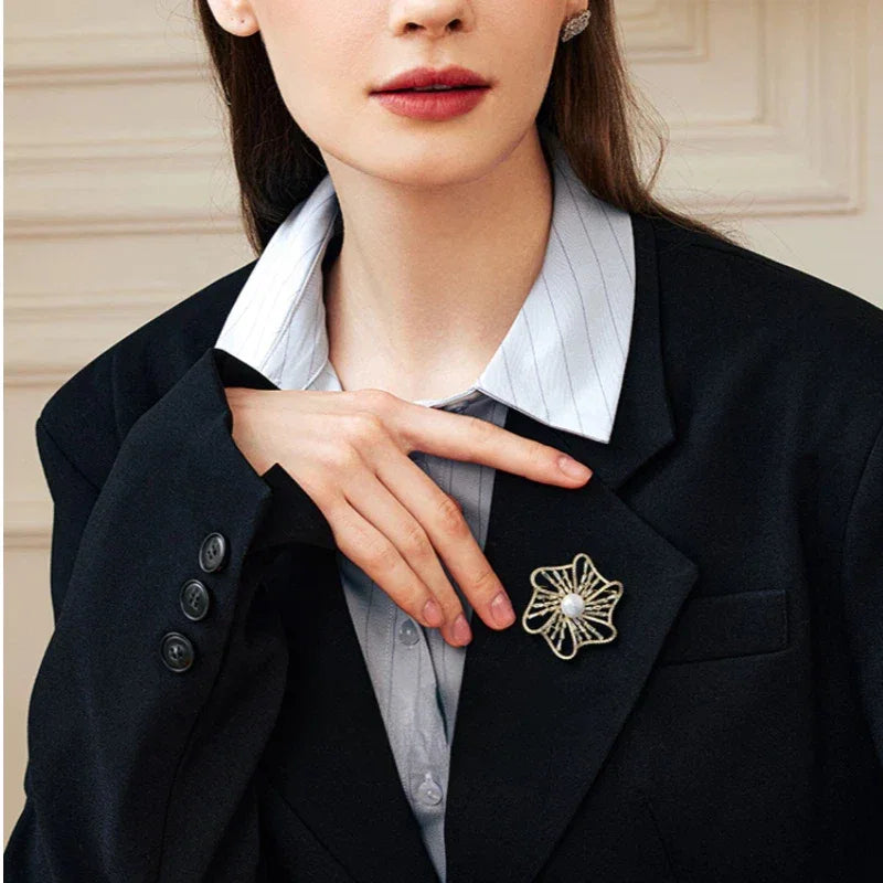 Pearl Openwork Camellia Brooch — waist-up blazer-worn portrait beside the model's hand