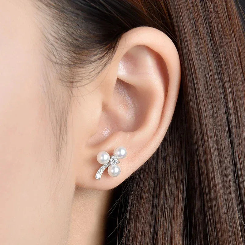 Three-Pearl Bow Stud Earrings in Platinum-Plated S925 Silver — right-ear worn close-up showing scale