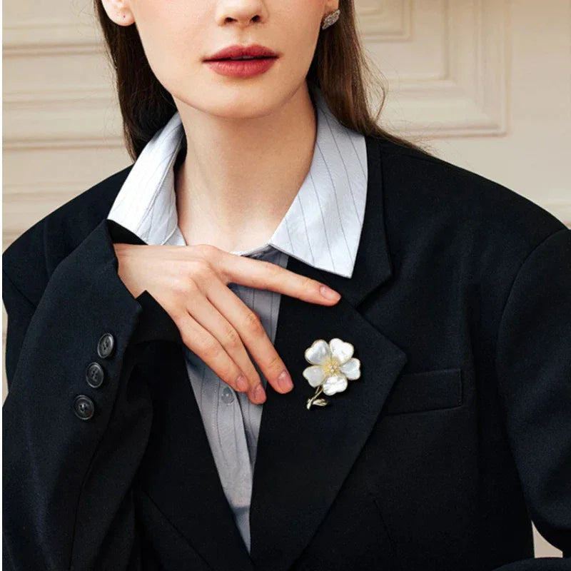Mother-of-Pearl Five-Petal Flower Brooch — waist-up blazer-worn portrait beside the model's hand