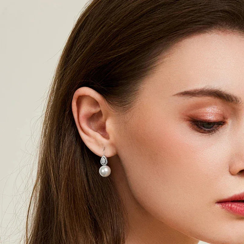 Pearl Teardrop Halo Earrings — left-ear worn portrait with the face angled downward