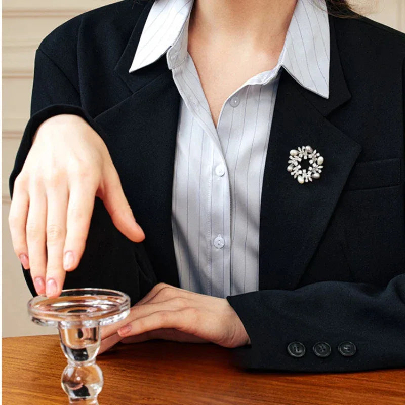 Pearl and Cubic Zirconia Olive Leaf Wreath Brooch — brooch worn on a black blazer beside a table setting