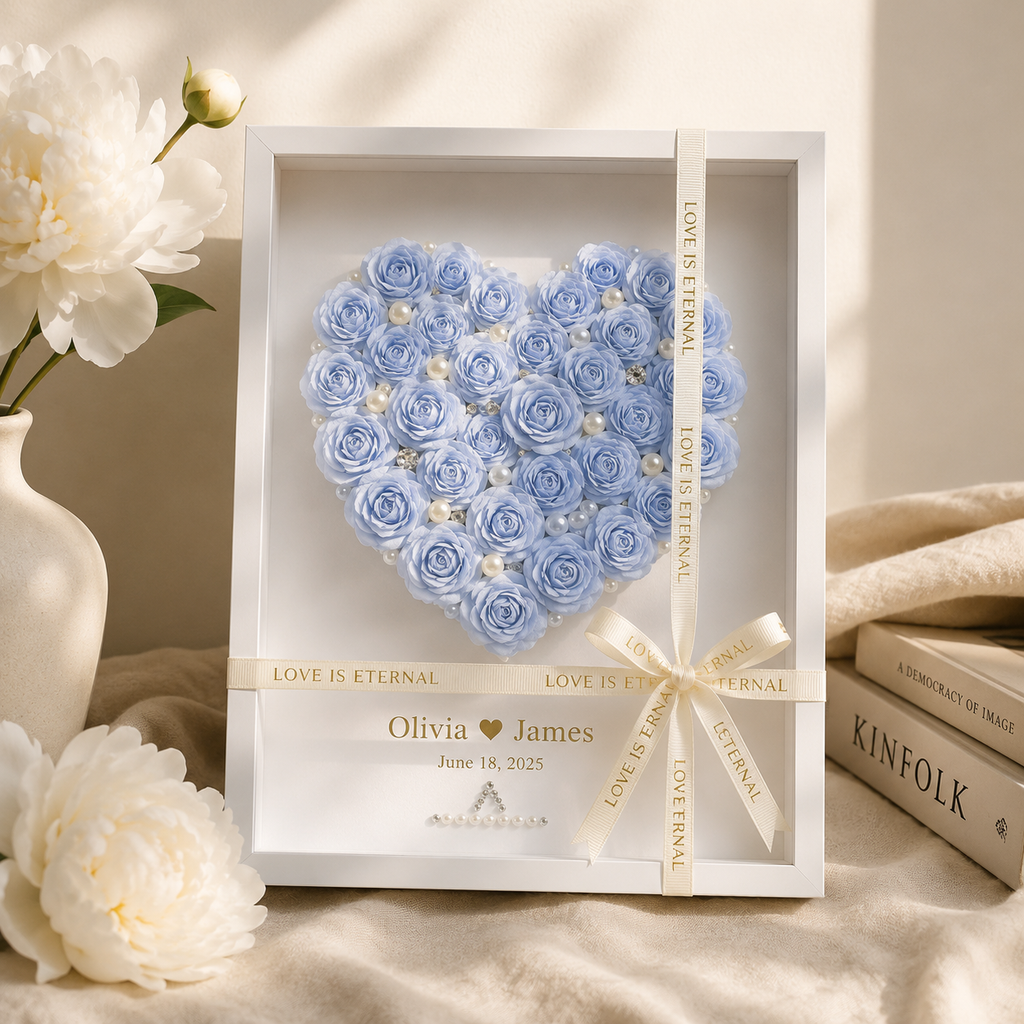 Personalized blue paper rose heart shadow box displayed on a walnut console table beside a lit candle champagne flute
