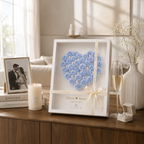 Romantic lifestyle flat lay of personalized blue paper rose heart shadow box surrounded by handwritten love letter vow