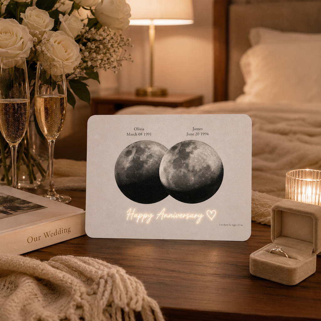 Personalized overlapping double moon phase film card on walnut bedside table beside Our Wedding album two champagne