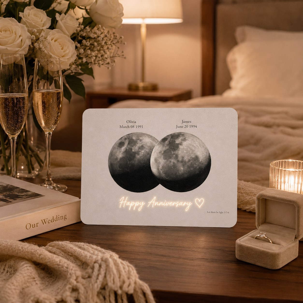 Personalized overlapping double moon phase film card on walnut bedside table beside Our Wedding album two champagne