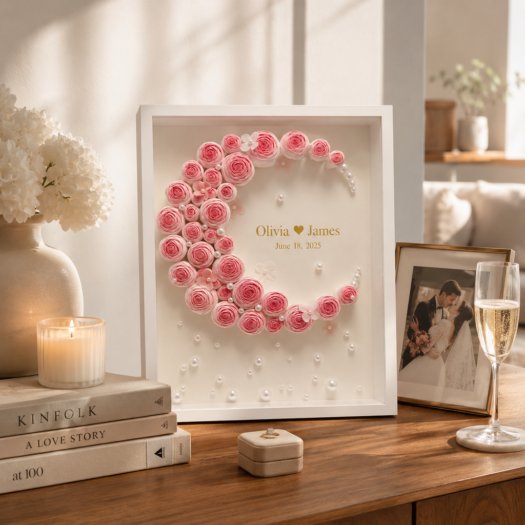 Lifestyle display of personalized paper rose monogram shadow box on a walnut console table beside a lit candle champagne