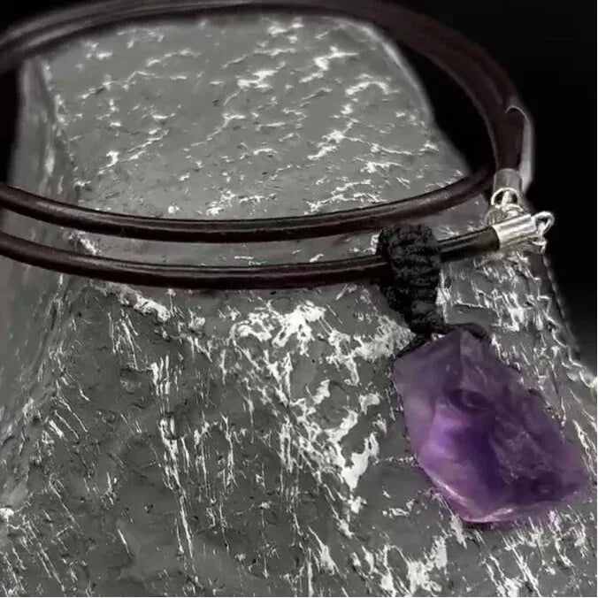 raw amethyst stone cord necklace stone and cord detail on a textured surface