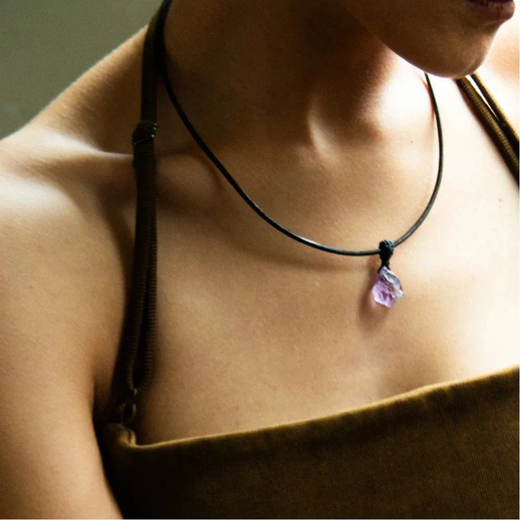 raw amethyst stone cord necklace worn at the neckline in warm light