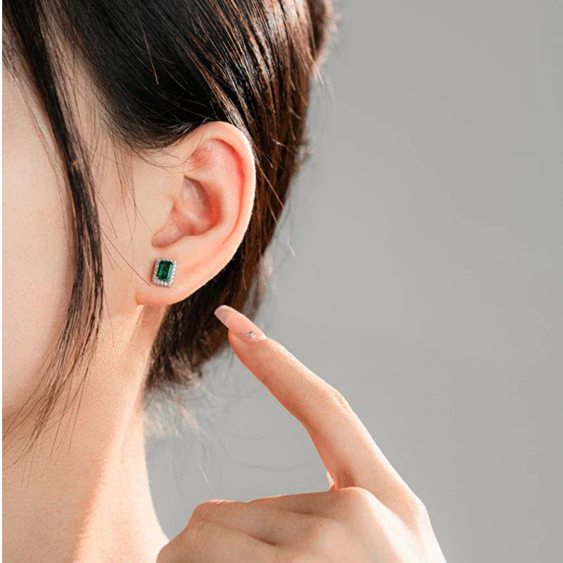 Rectangular Emerald Halo Stud Earrings worn on the ear from a second angle