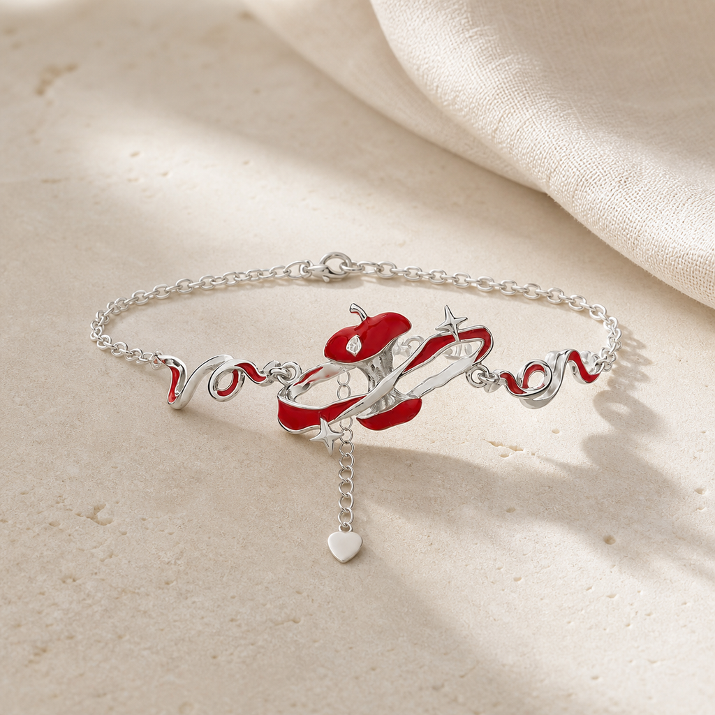 Silver chain bracelet with a red apple, flowing enamel lines and star accents on beige stone