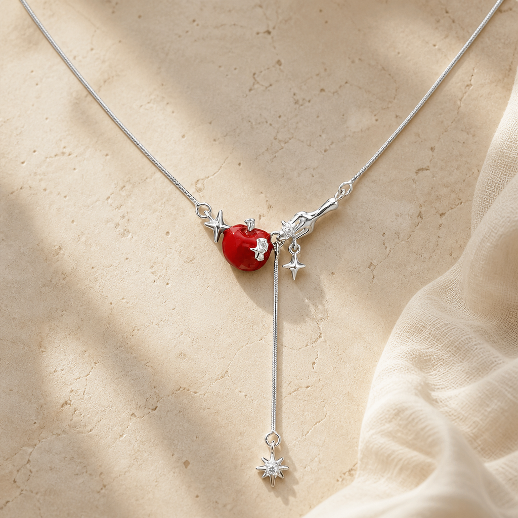 Silver necklace with a red apple, star accents and a long clear starburst drop on beige stone