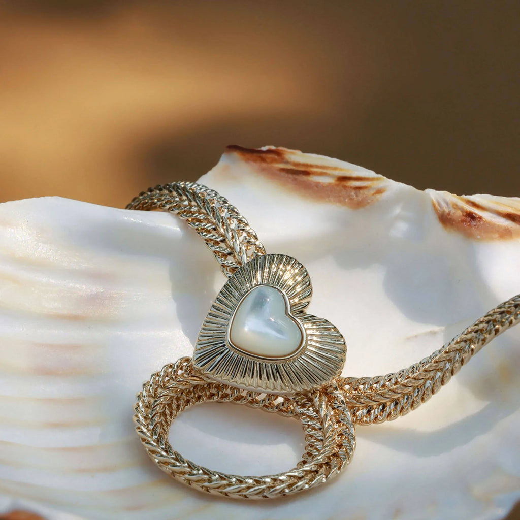 Double-Chain Pearl Heart Necklace — necklace coiled on a dark display surface