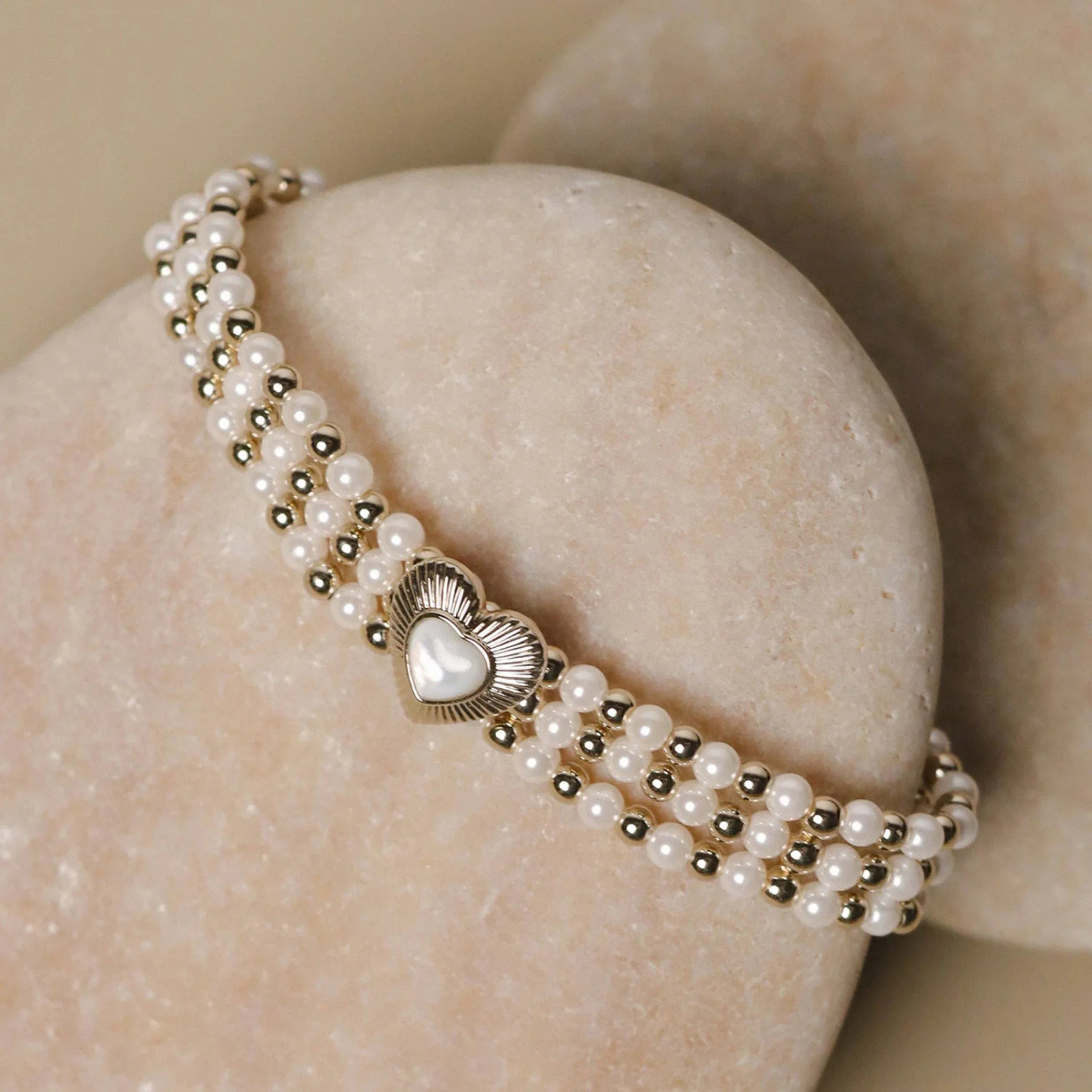 Multi-Row Pearl Heart Stretch Bracelet — bracelet wrapped around a pale stone display
