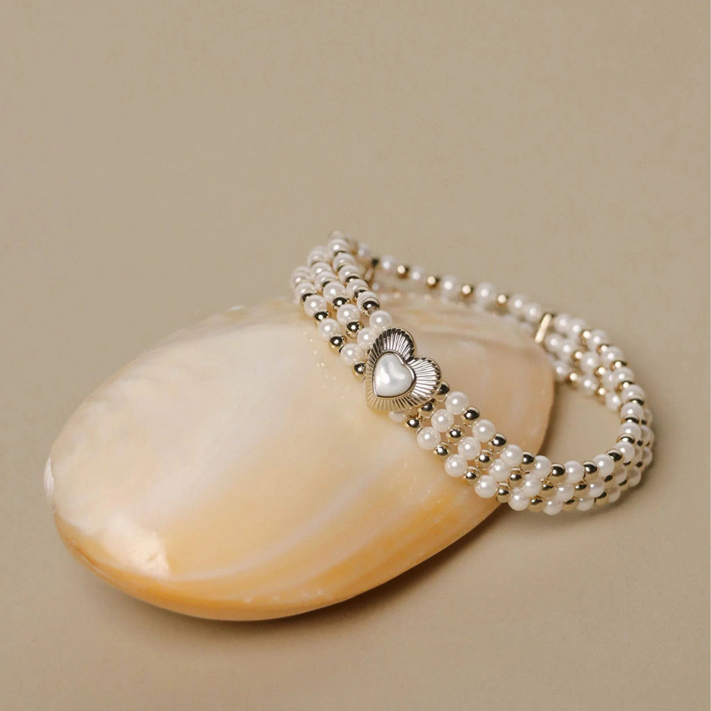 Multi-Row Pearl Heart Stretch Bracelet — bracelet displayed beside a pale shell
