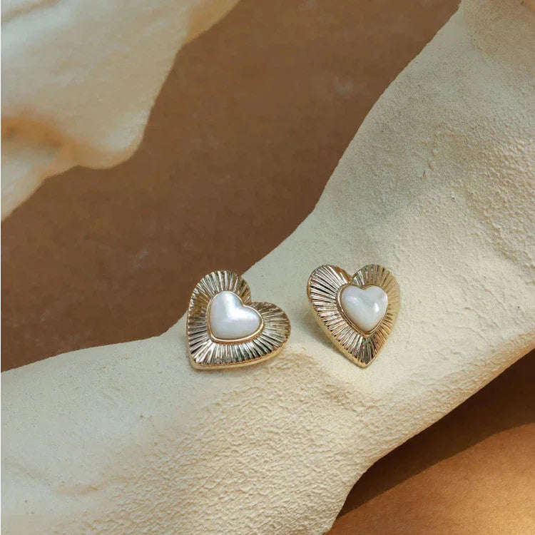 Ridged Pearl Heart Stud Earrings — earrings displayed on a pale textured surface