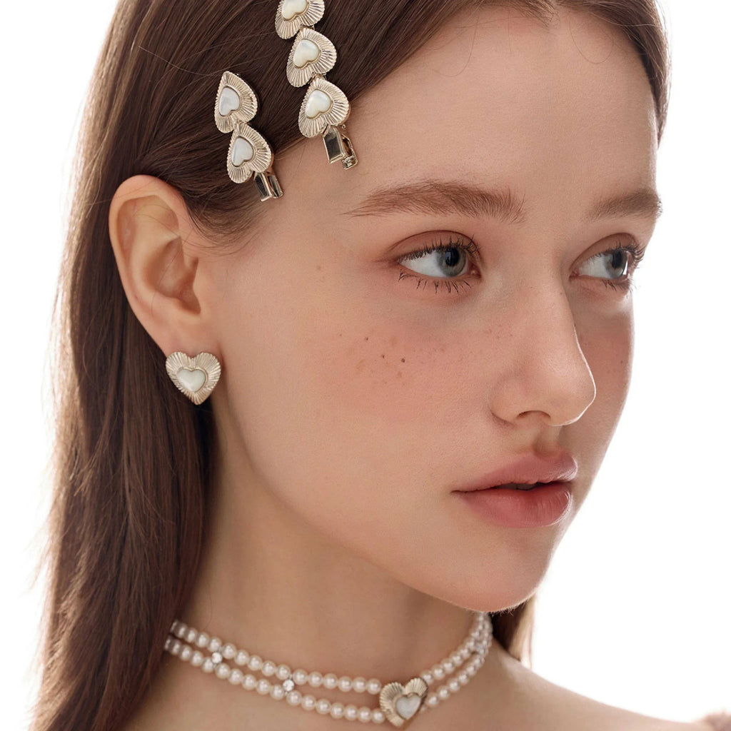 Ridged Pearl Heart Stud Earrings — front model portrait with floral hair accessories