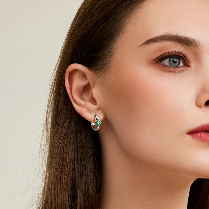 Rhombus Emerald Huggie Hoop Earrings worn on the ear in a close-up
