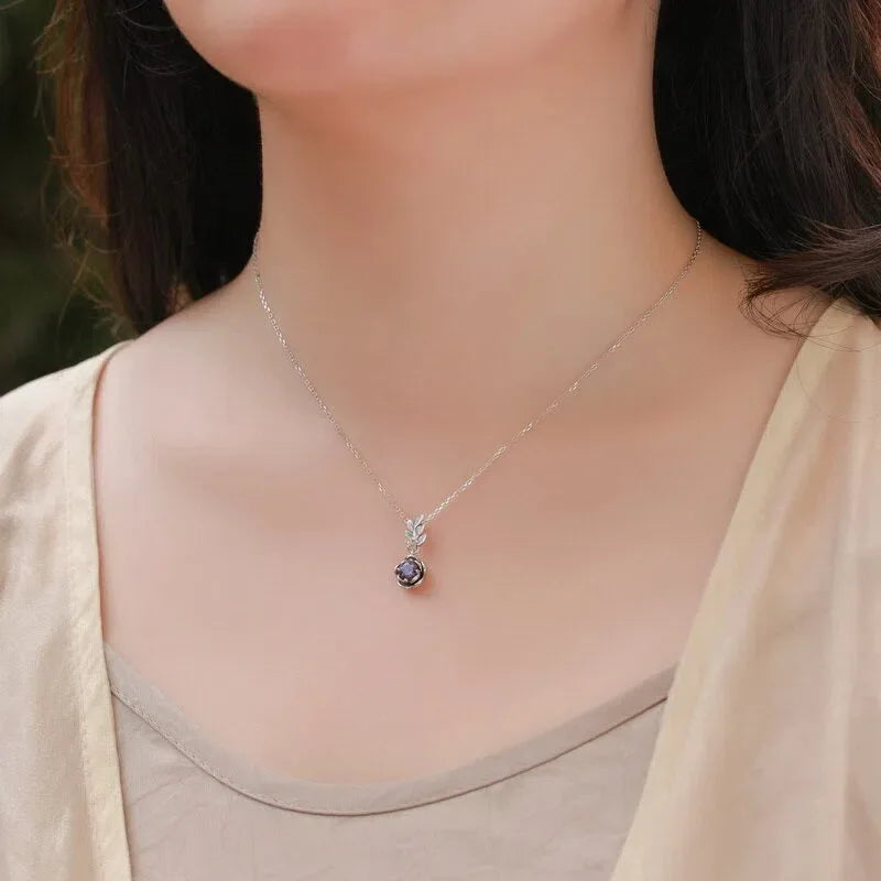 Round Alexandrite rose pendant necklace with a leaf connector, shown worn in a close lifestyle view