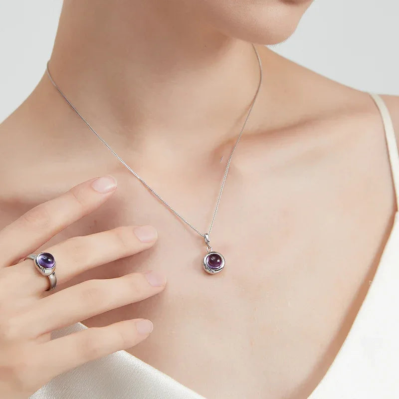 round amethyst bezel pendant necklace worn at the neckline in a close-up