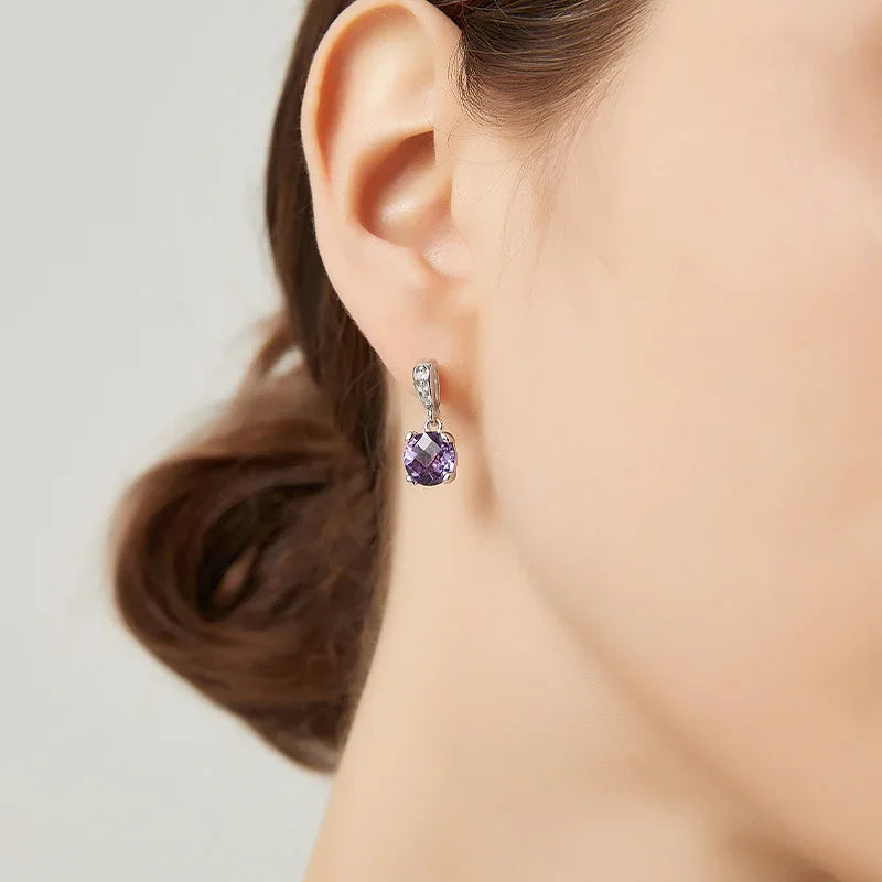 round amethyst drop earrings worn on the ear in a close-up