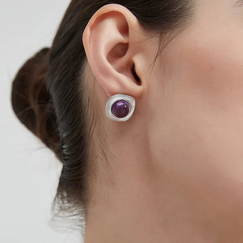 round amethyst stud earrings worn on the ear in a close-up