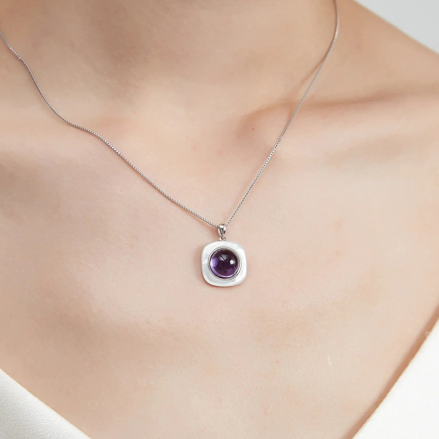 round amethyst pendant necklace worn at the neckline in a close-up