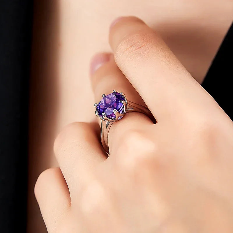 round amethyst solitaire ring worn on the hand in a close-up