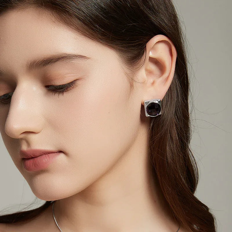 round amethyst stud earrings worn on the ear in a close-up