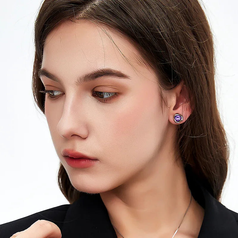 round amethyst stud earrings worn on the ear in a close-up
