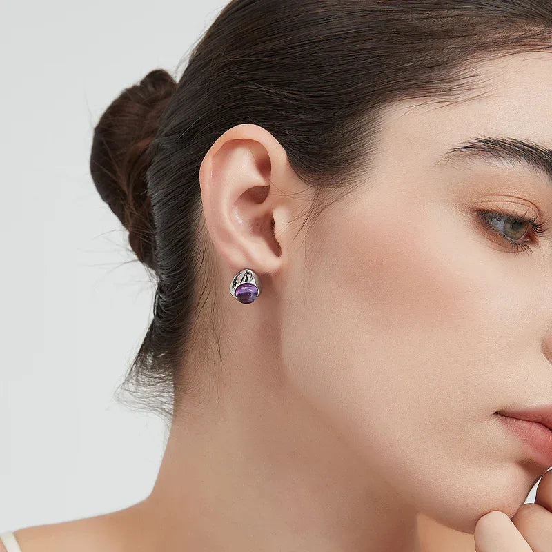 round amethyst stud earrings styled portrait showing the earrings for scale