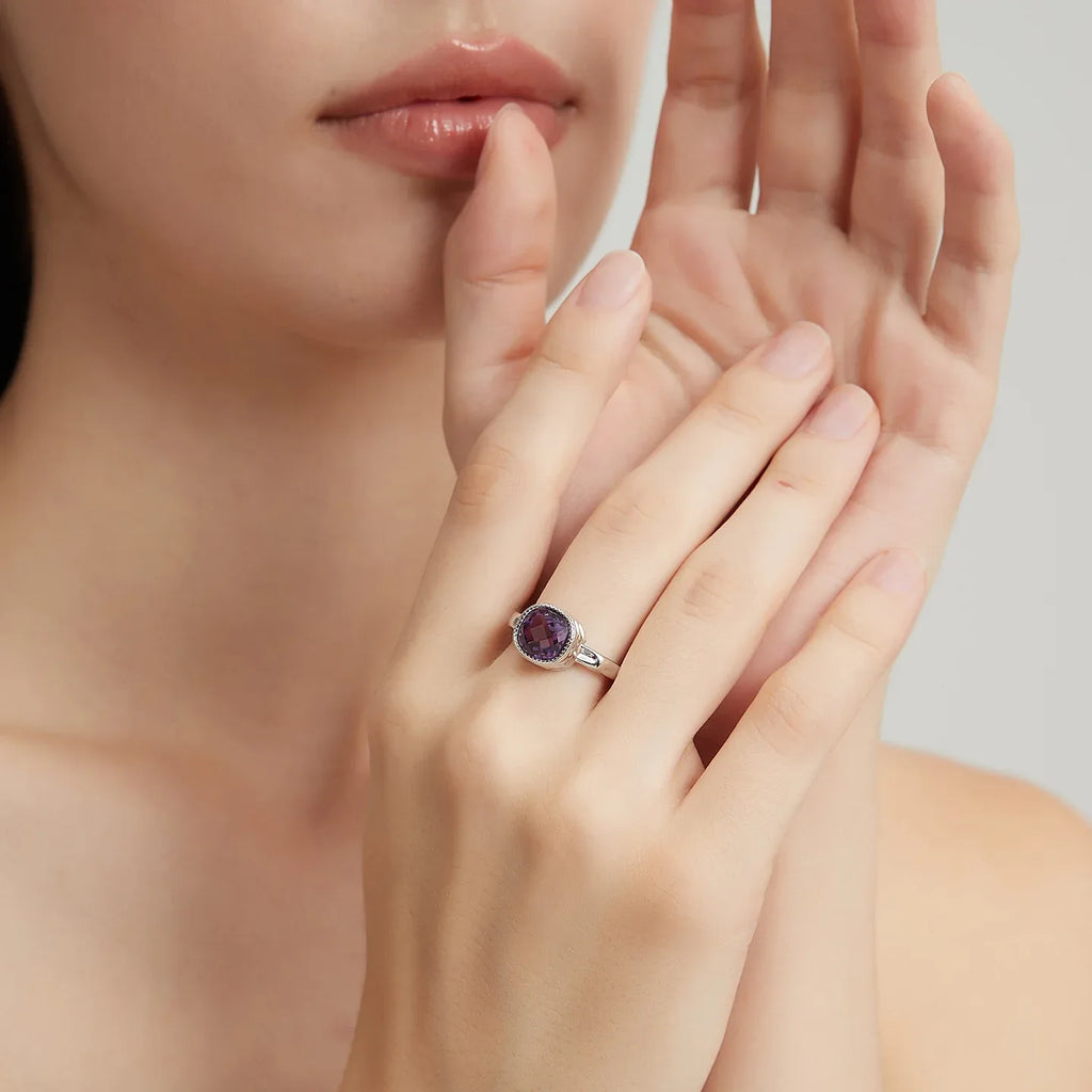 round amethyst halo ring worn on the hand in a close-up