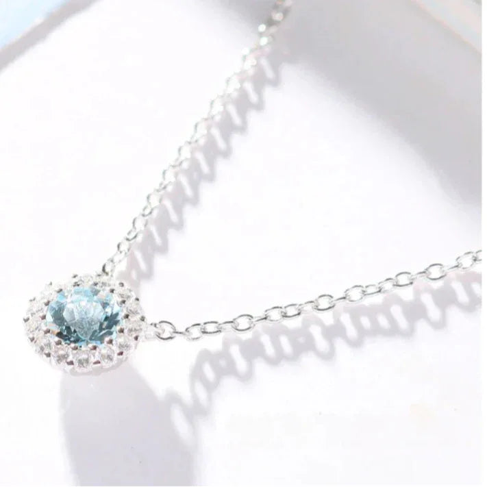 Round Aquamarine Halo Pendant Necklace pendant and chain detail on a light background