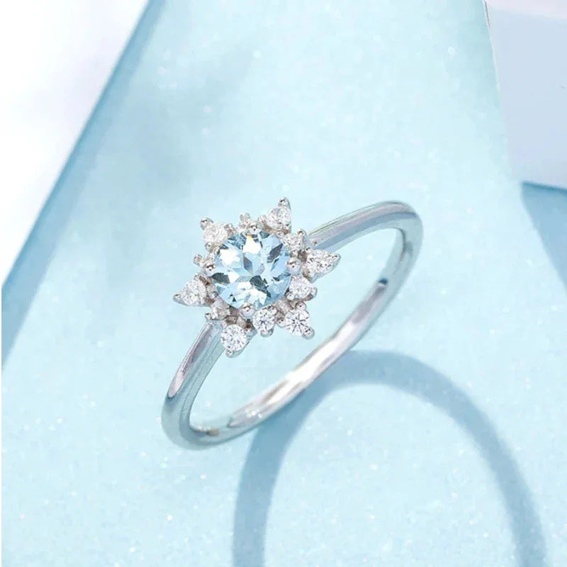 Round Aquamarine Snowflake Halo Ring worn on the hand in a close-up