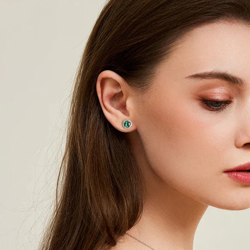 Round Emerald Halo Stud Earrings worn on the ear from a second angle