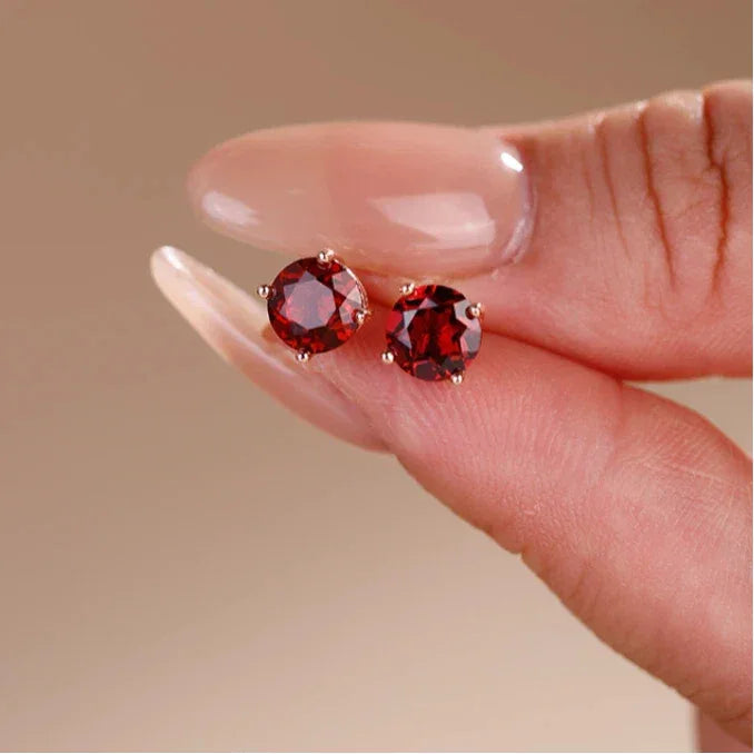 Round Garnet Four-Prong Stud Earrings side view held between the fingers