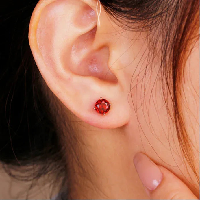 Round Garnet Four-Prong Stud Earrings worn on the hand in a close-up