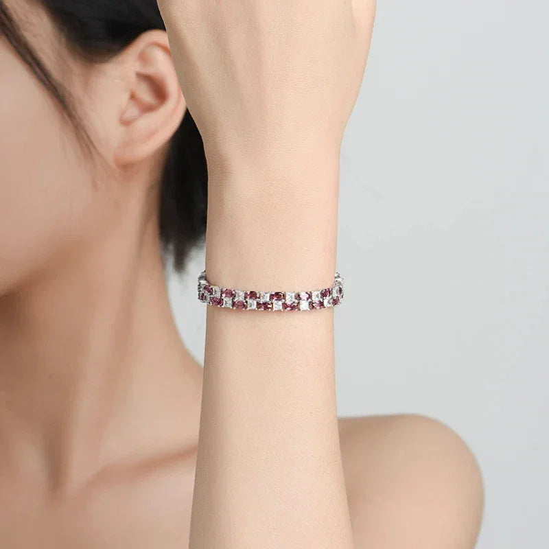 Round Garnet Tennis Bracelet bracelet arranged on a jewelry display
