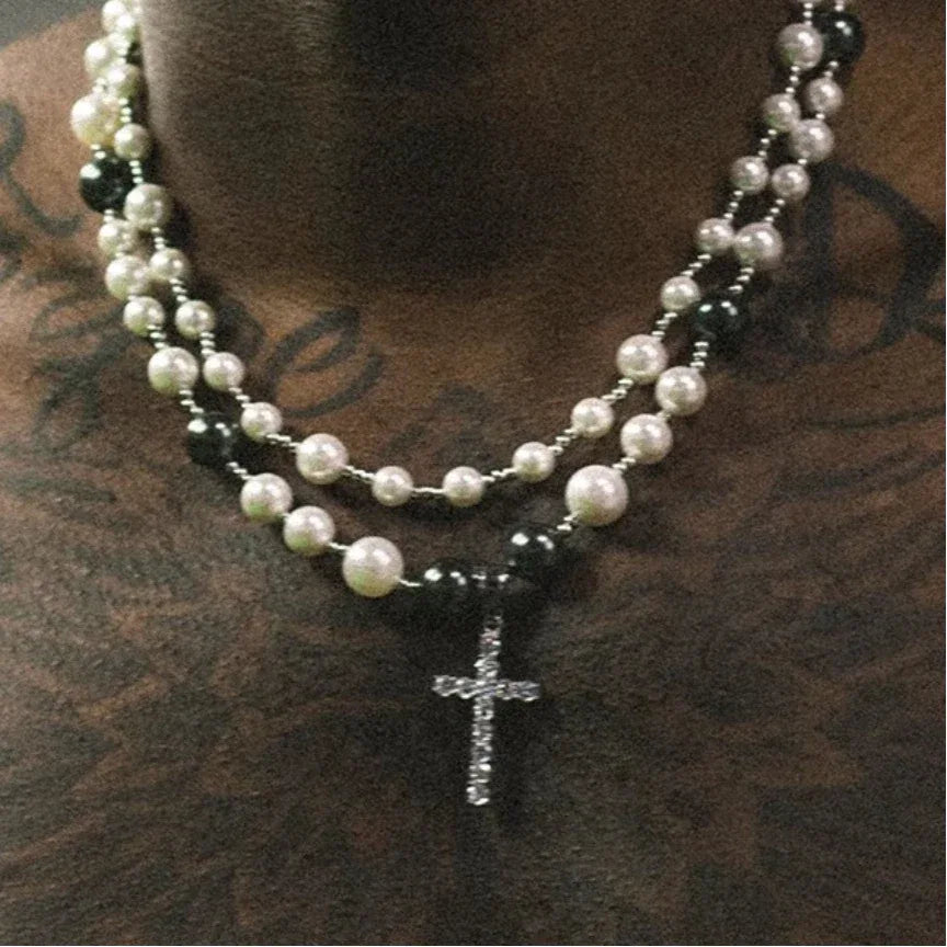 Black and White Pearl Double-Strand Cross Necklace — necklace displayed against a brown textured surface