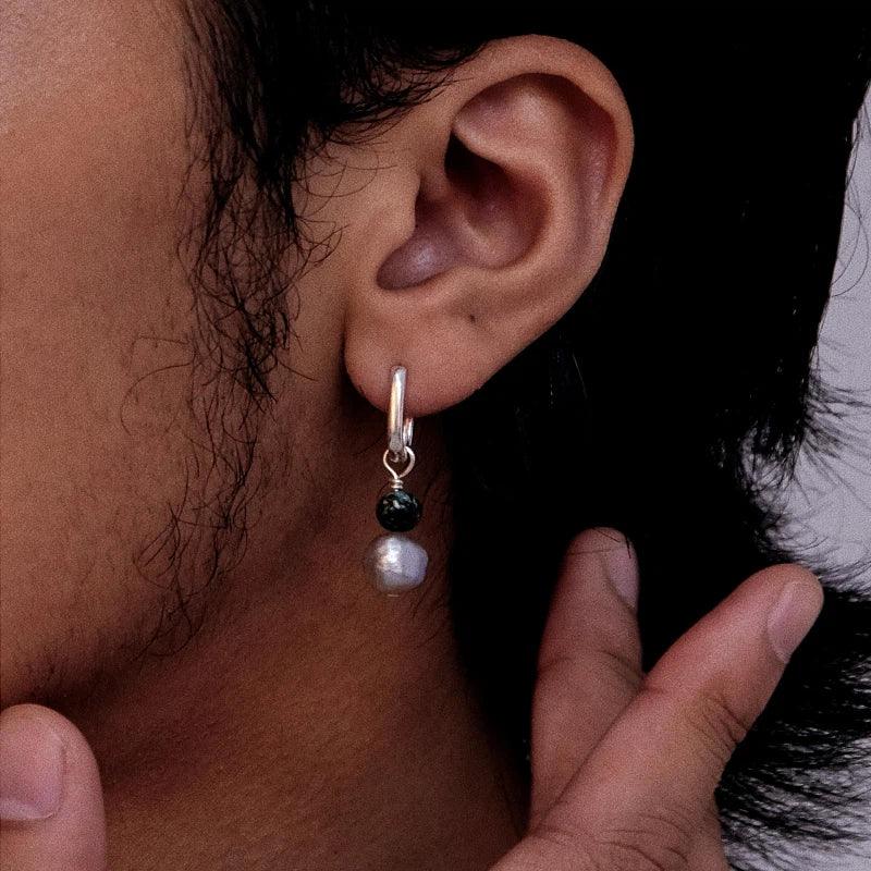 S925 Silver Pearl Drop Earrings with Green Bead Accent — left-ear worn close-up with a fingertip indicating scale