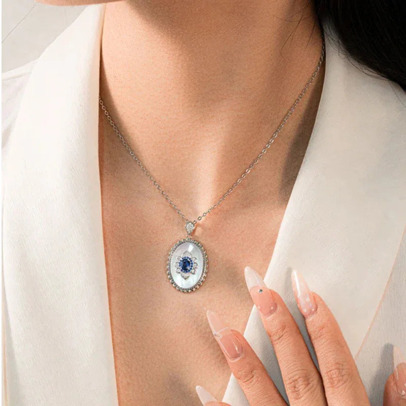 Sapphire and Mother-of-Pearl Oval Pendant Necklace — neckline-worn view with a hand near the pendant