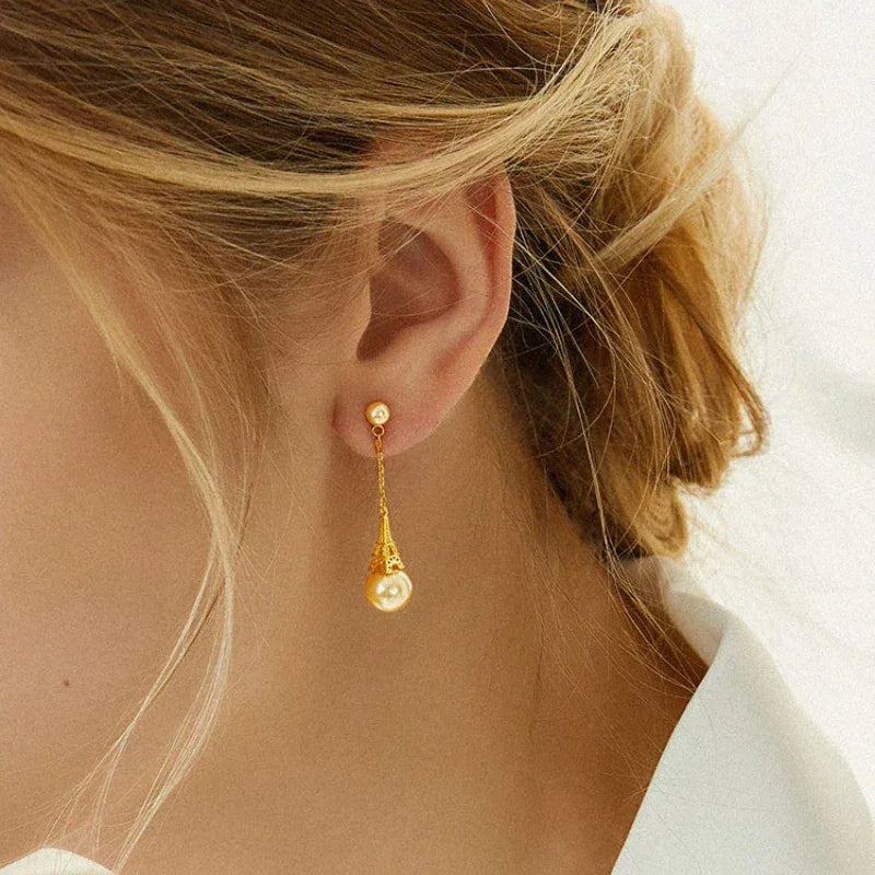 Shell Pearl Eiffel Tower Drop Earrings — close gold-tone worn view showing the drop length