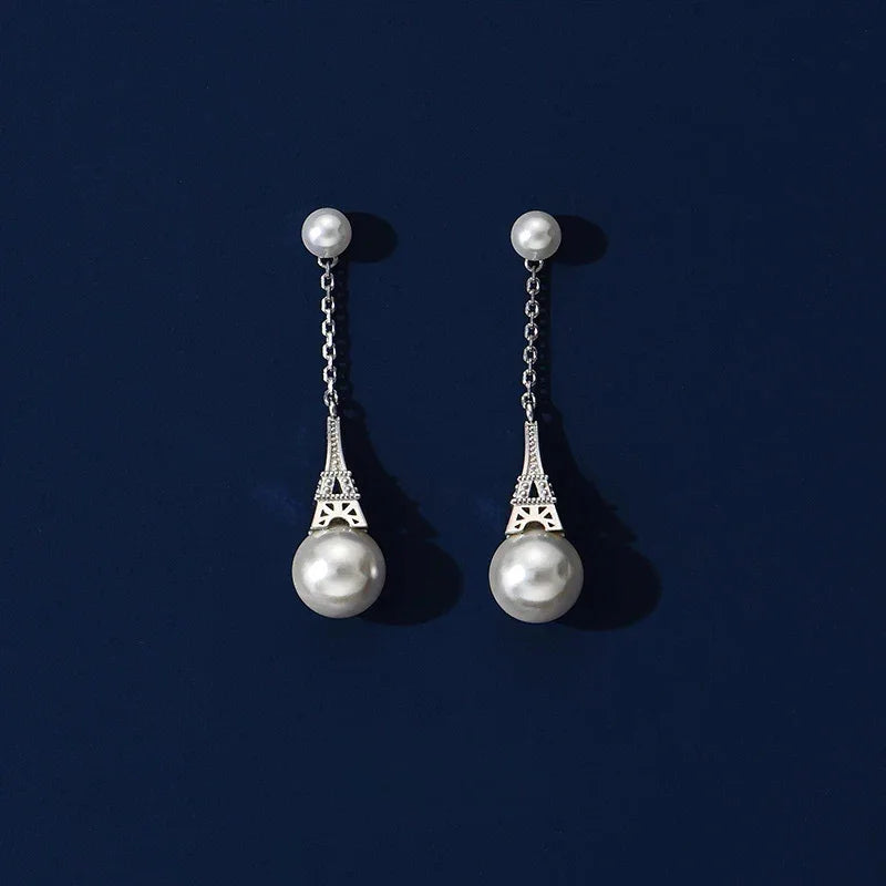 Shell Pearl Eiffel Tower Drop Earrings — silver-tone pair displayed on a dark background