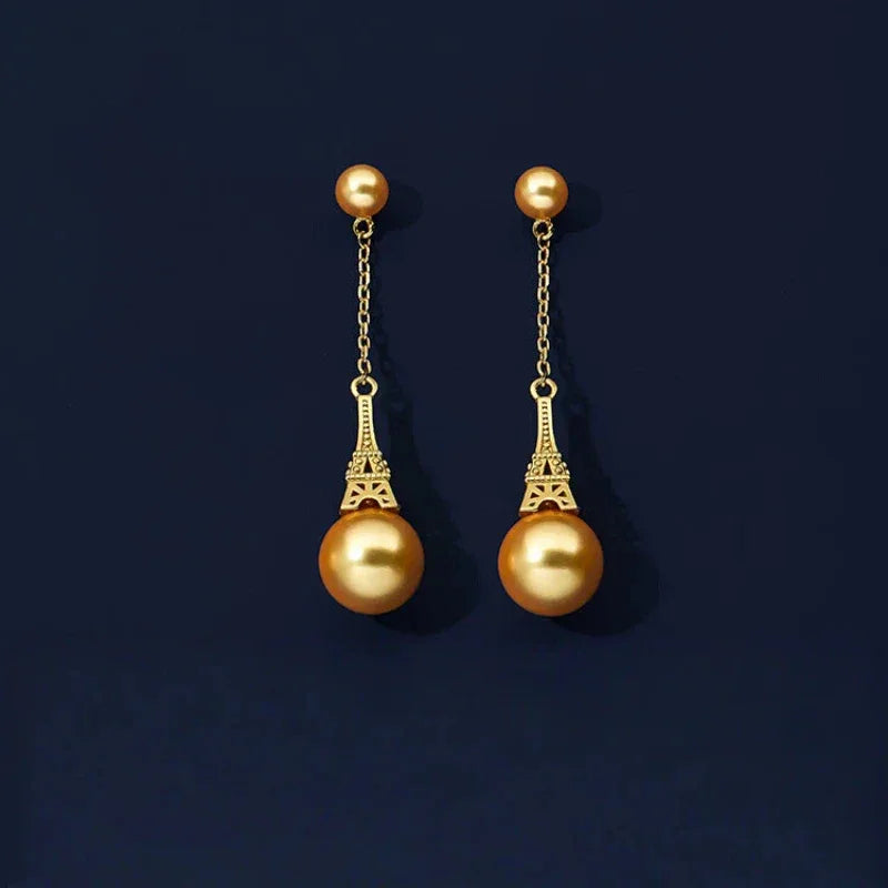 Shell Pearl Eiffel Tower Drop Earrings — gold-tone pair displayed on a dark background