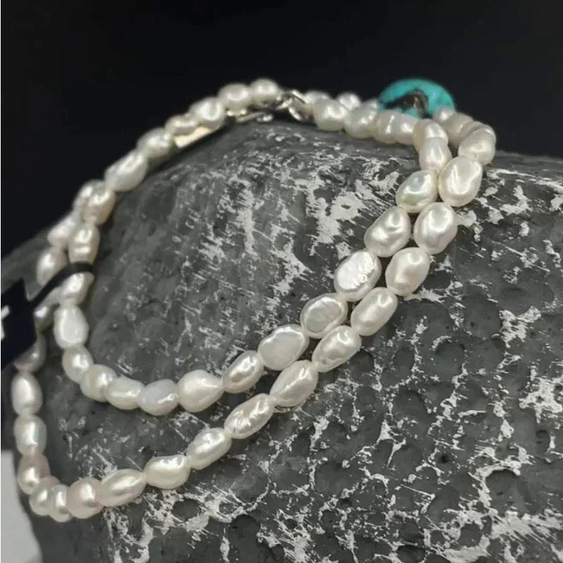 Pearl Strand Necklace with Turquoise Center Bead in S925 Silver - pearl strand draped over a dark textured stone