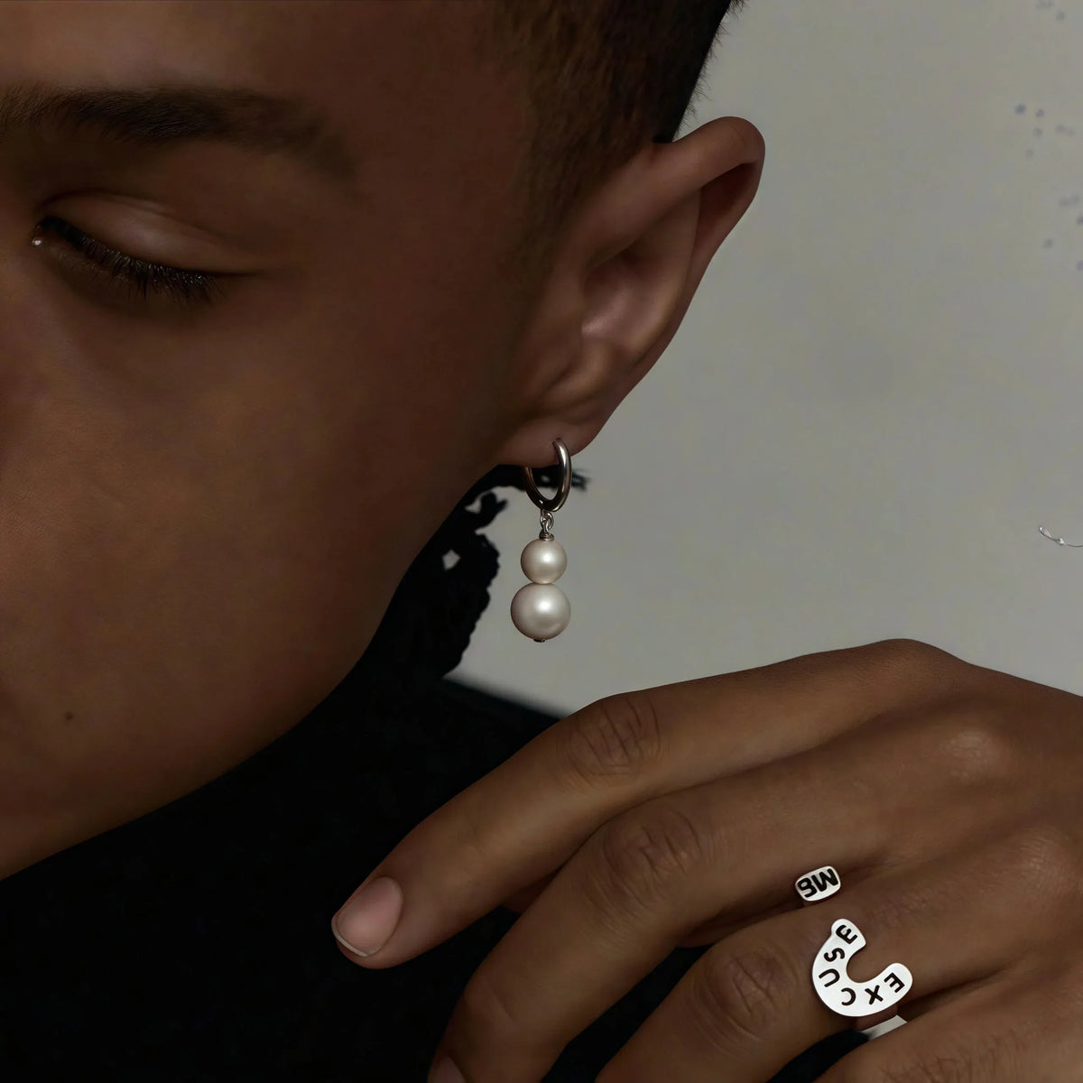 Double-Pearl Drop Hoop Earrings — model portrait with the earring beside a raised hand