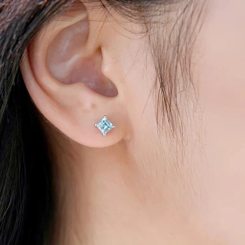 Square-Cut Aquamarine Stud Earrings worn on the ear in a close-up