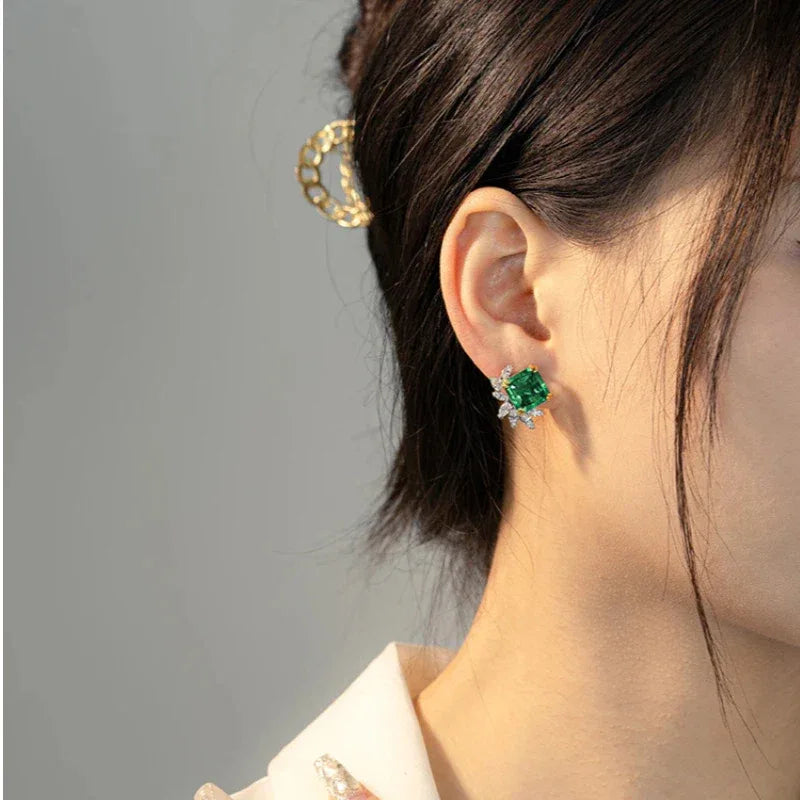 Square-Cut Emerald Floral Stud Earrings worn on the ear in a close-up