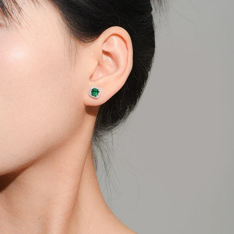 Square Emerald Halo Stud Earrings styled ear view showing scale